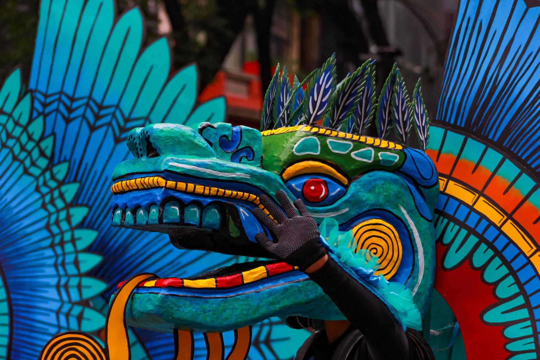 a person wearing blue green and yellow dragon head during a parade