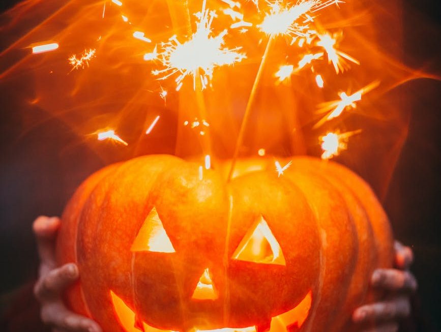 Les traditions d'Halloween à travers le monde. Citrouille sculptée illuminée de l'intérieur avec des étincelles s'échappant du sommet, tenue dans l'obscurité.