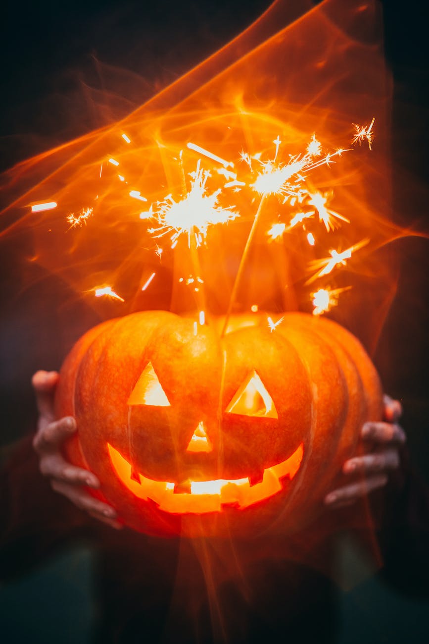 Les traditions d'Halloween à travers le monde. Citrouille sculptée illuminée de l'intérieur avec des étincelles s'échappant du sommet, tenue dans l'obscurité.