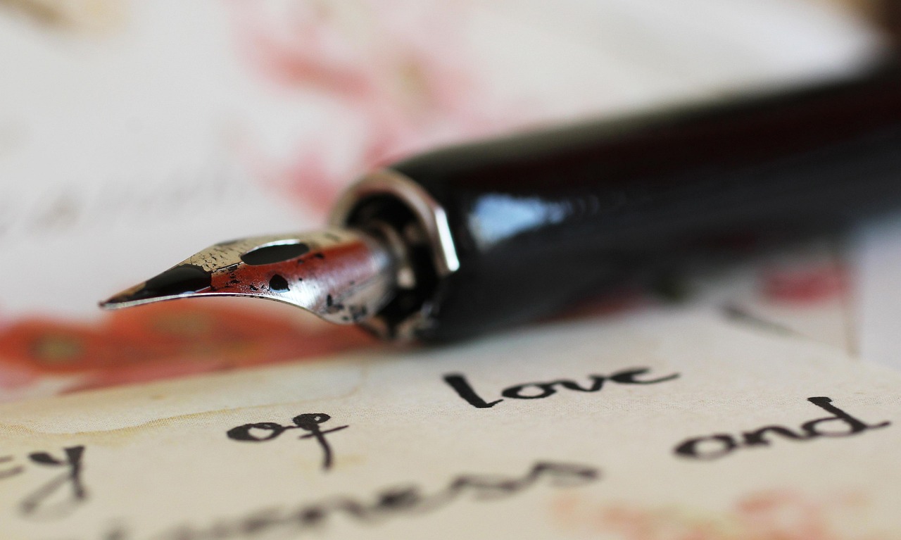 Gros plan sur une plume de stylo posée sur une feuille manuscrite, illustrant l’écriture d’une biographie d’auteur avec une calligraphie élégante.