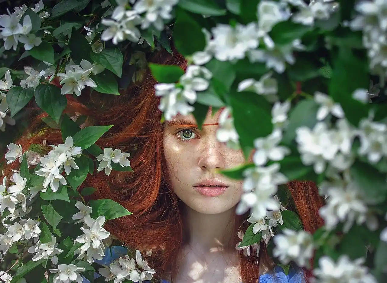 Portrait poétique d’une femme rousse entourée de fleurs blanches, symbolisant l’univers imaginaire et émotionnel des contes pour adultes.