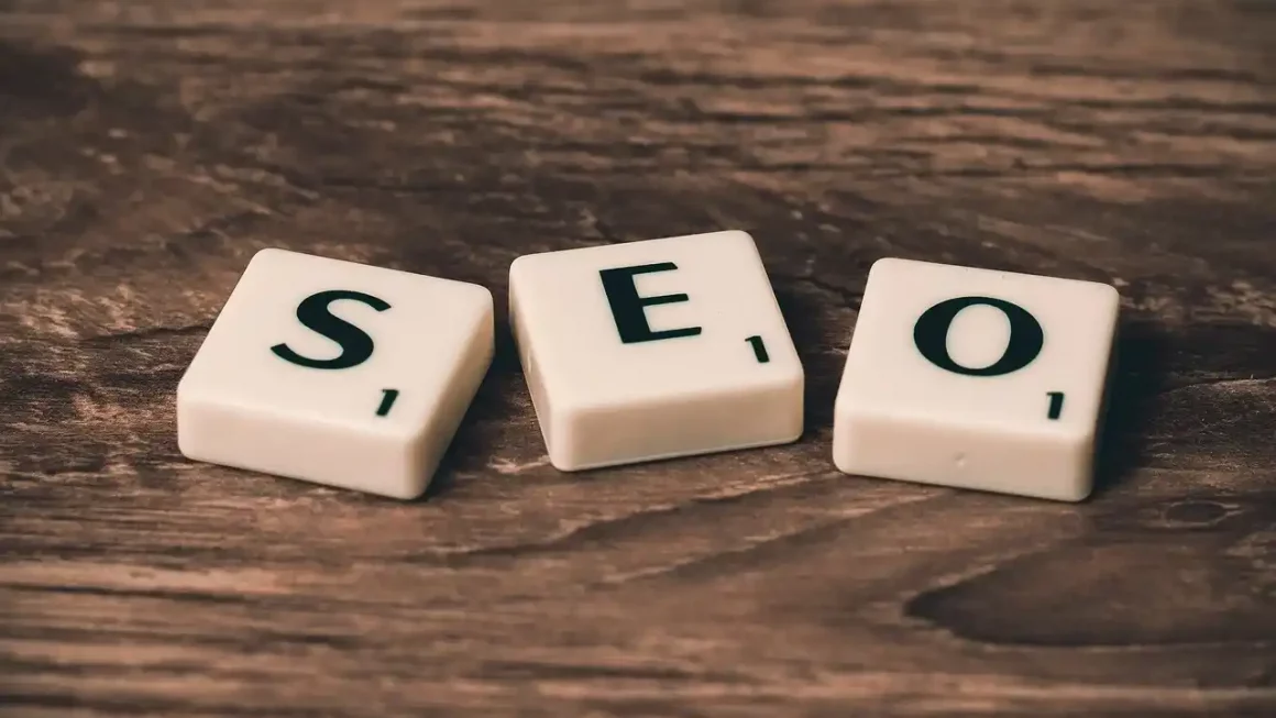 Photo de lettres formant « SEO » sur fond bois, illustrant l’article pour « Optimiser le référencement de son livre en ligne »
