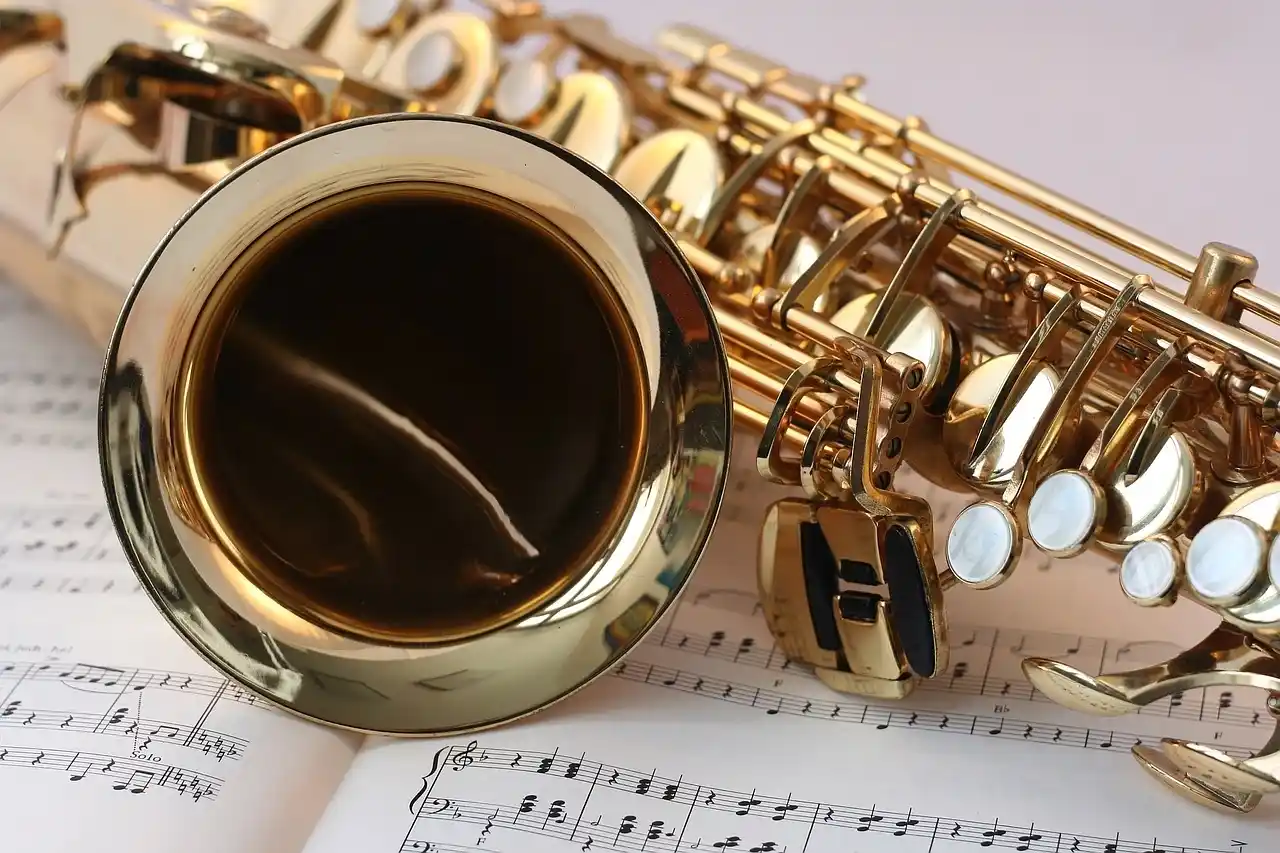 Saxophone doré posé sur des partitions musicales – symbole de la diversité des instruments célébrés lors de l'Histoire de la Fête de la Musique.