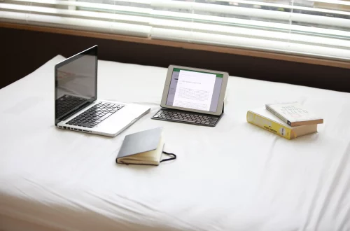 Auteur face à ses outils d'écriture et avec ses croyances limitantes : ordinateur, tablette, carnet et livres posés sur un bureau.