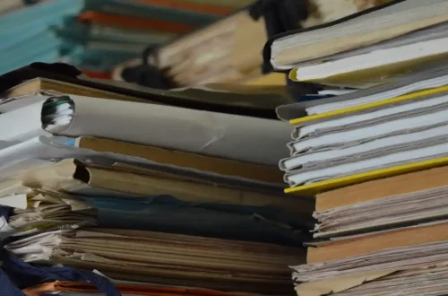 Pile de dossiers administratifs entassés symbolisant le labyrinthe bureaucratique vécu par les agents en arrêt maladie et se suicide dans la Fonction publique