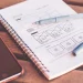 Carnet de croquis avec wireframe de site web dessiné à la main, smartphone et stylos - gagner en visibilité sur le web en tant qu'auteur (visibilité web auteur).